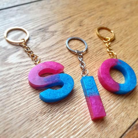 A table top with three key rings on. There is an S, I and O in pink blue ombre. 